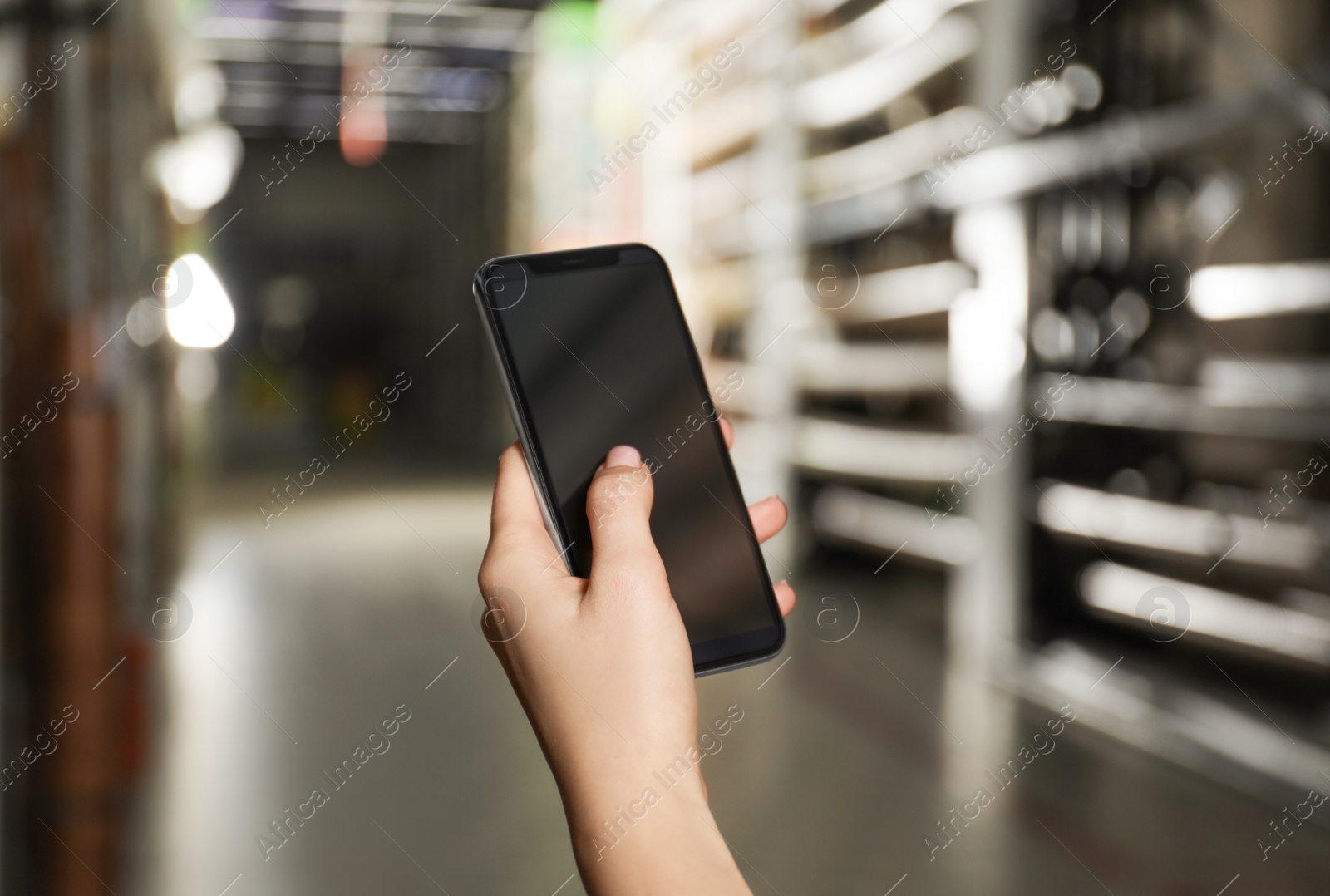 Photo of Woman with smartphone in wholesale warehouse, closeup. Space for design