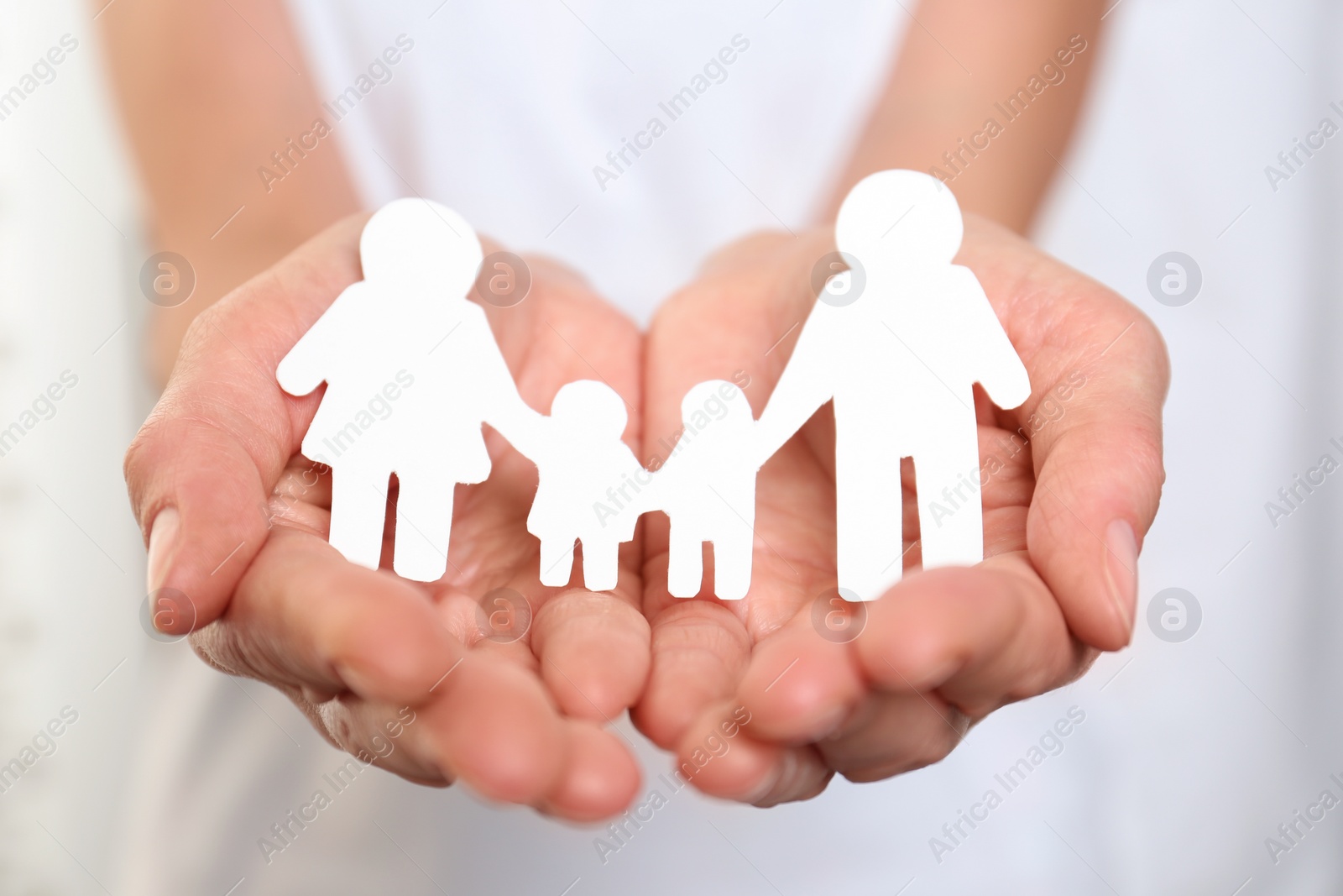 Photo of Young woman holding paper family figure, closeup of hands