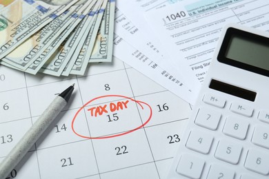 Photo of Calendar with date reminder about tax day, documents, pen, calculator and money, above view