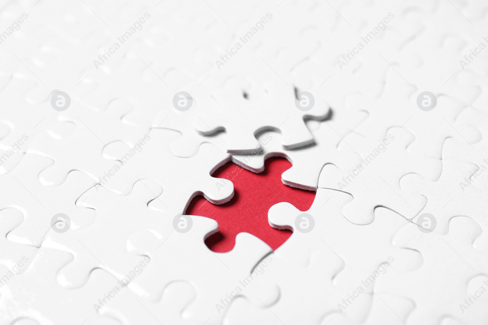 Photo of Blank white puzzle with separated piece on red background