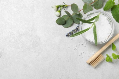 Photo of Bamboo toothbrush, sea salt and herbs on light grey table, flat lay. Space for text