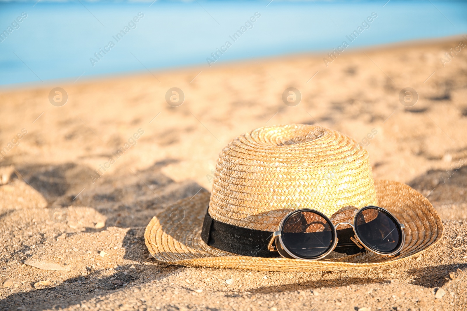 Photo of Straw hat and sunglasses on beach sand. Summer vacation