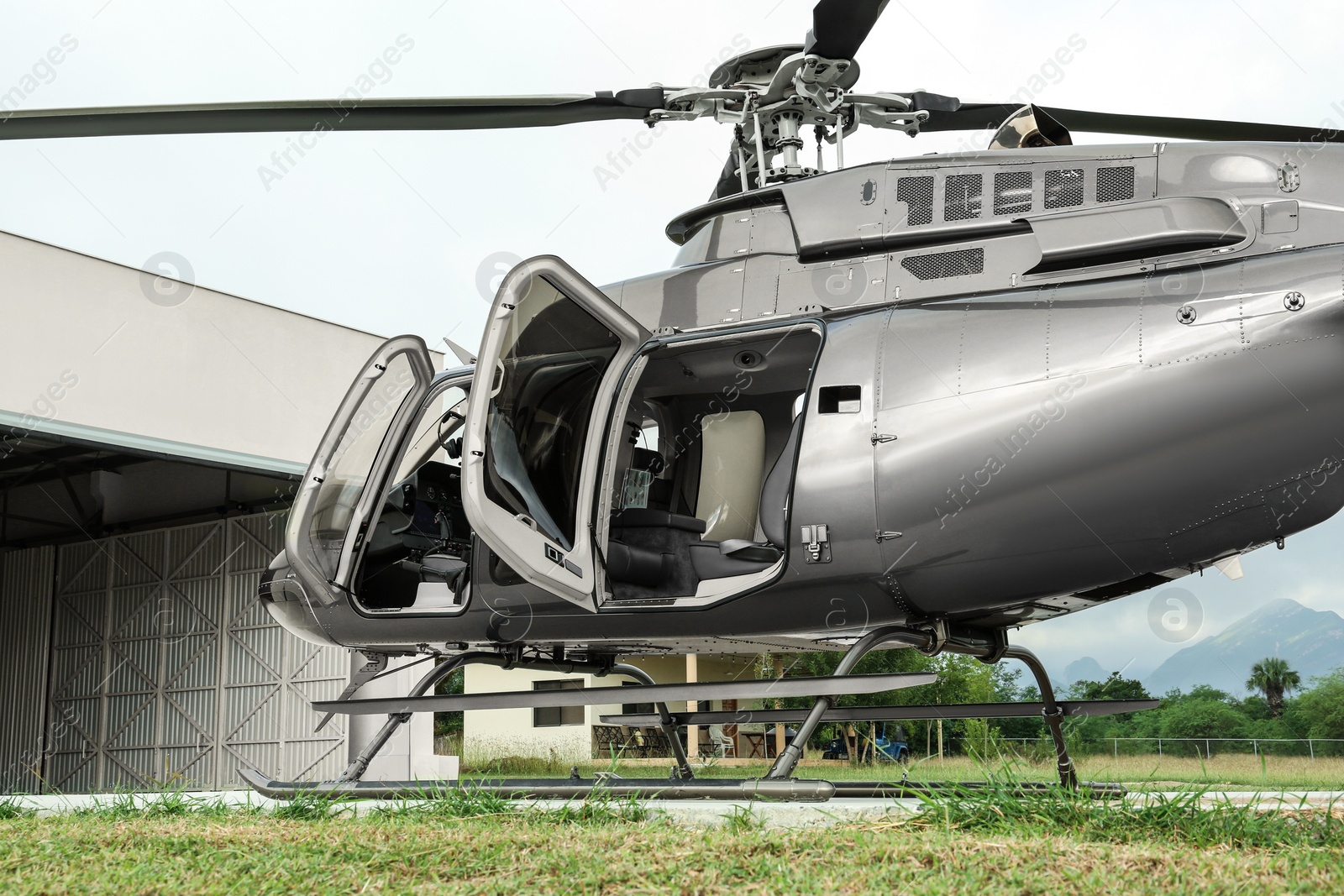 Photo of New helicopter with open cabin doors on helipad outdoors