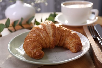 Photo of Tasty croissant served on wooden table, closeup