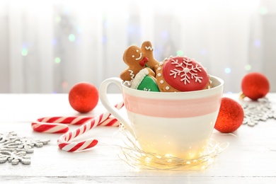 Photo of Cup with tasty homemade Christmas cookies on table