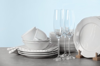 Photo of Set of clean dishes on table against light background