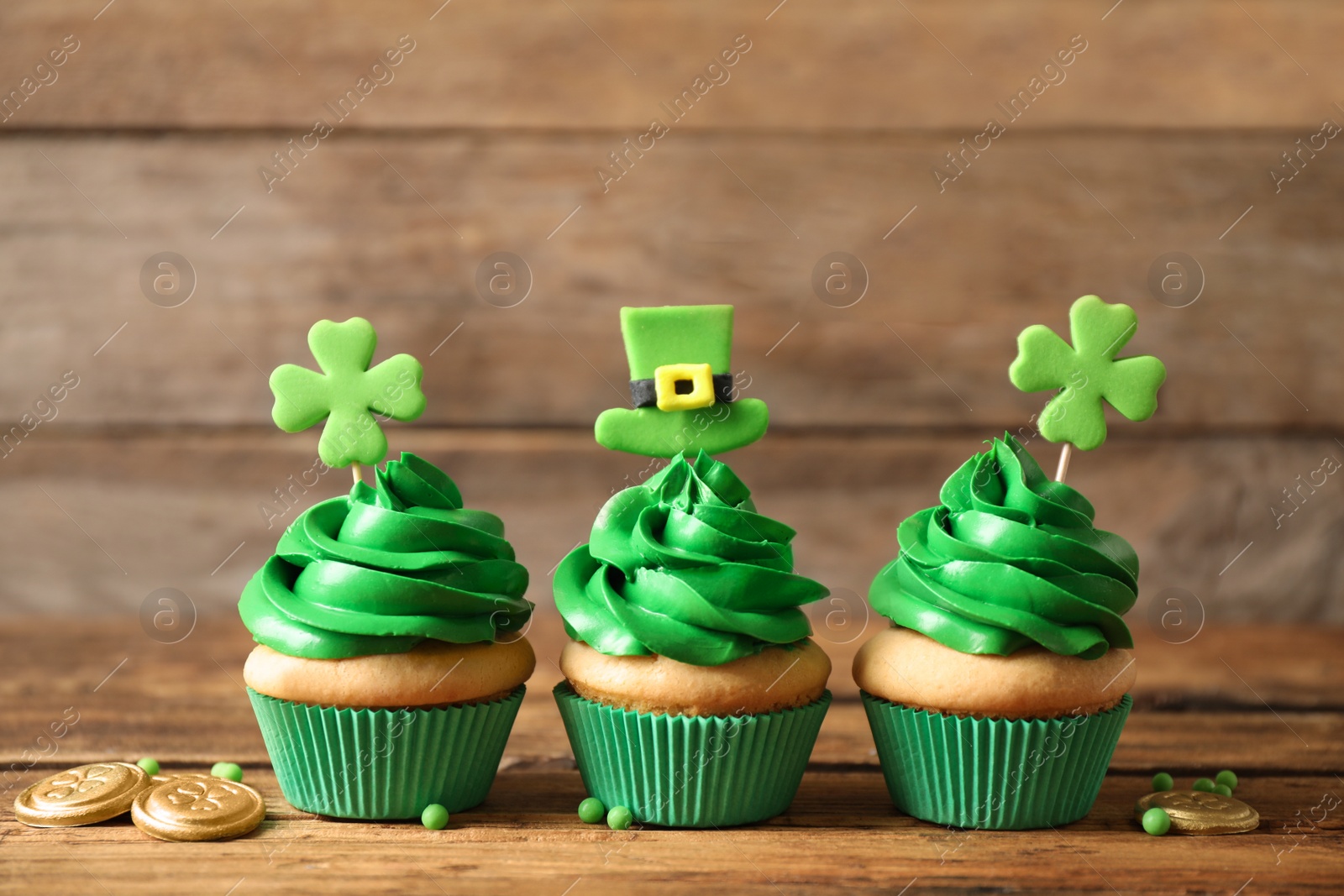 Photo of Decorated cupcakes and coins on wooden table. St. Patrick's Day celebration