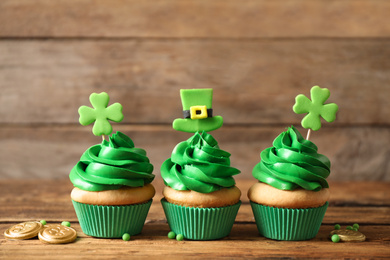 Photo of Decorated cupcakes and coins on wooden table. St. Patrick's Day celebration