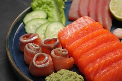 Photo of Tasty salmon slices, cucumber and tuna on table, closeup. Delicious sashimi dish