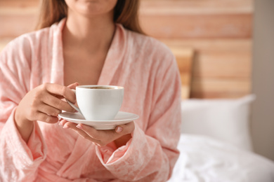 Photo of Woman with cup of hot coffee at home, closeup
