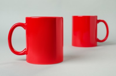 Two red ceramic mugs on light grey background