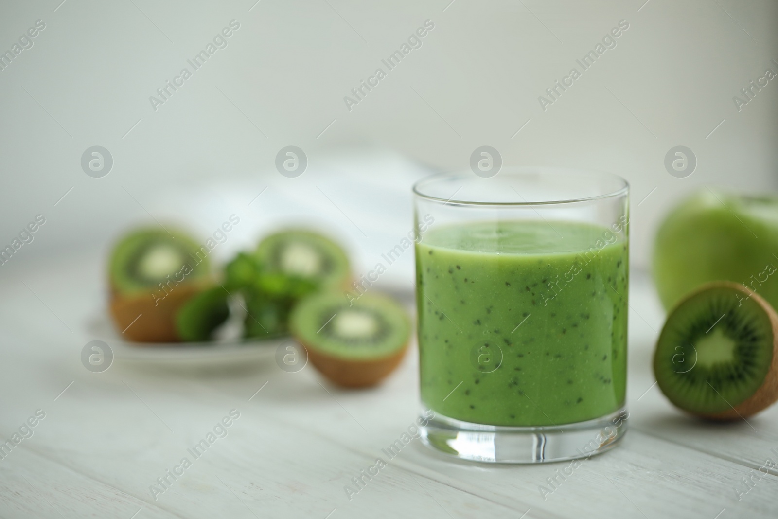 Photo of Delicious kiwi smoothie and fresh fruits on white wooden table. Space for text