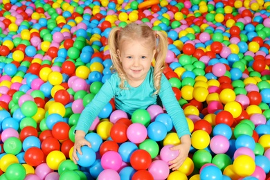 Photo of Cute child playing in ball pit indoors