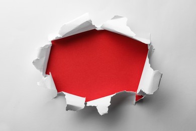 Hole in white paper on red background