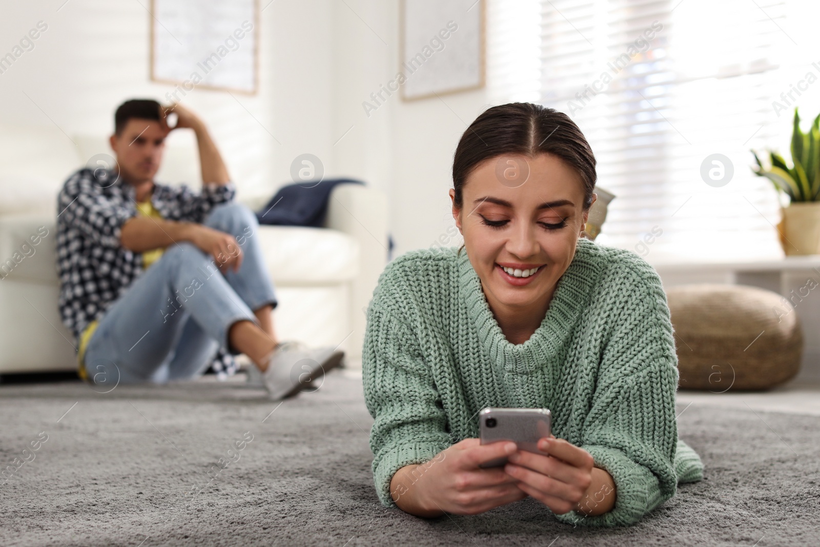 Photo of Woman preferring smartphone over spending time with her boyfriend at home. Jealousy in relationship