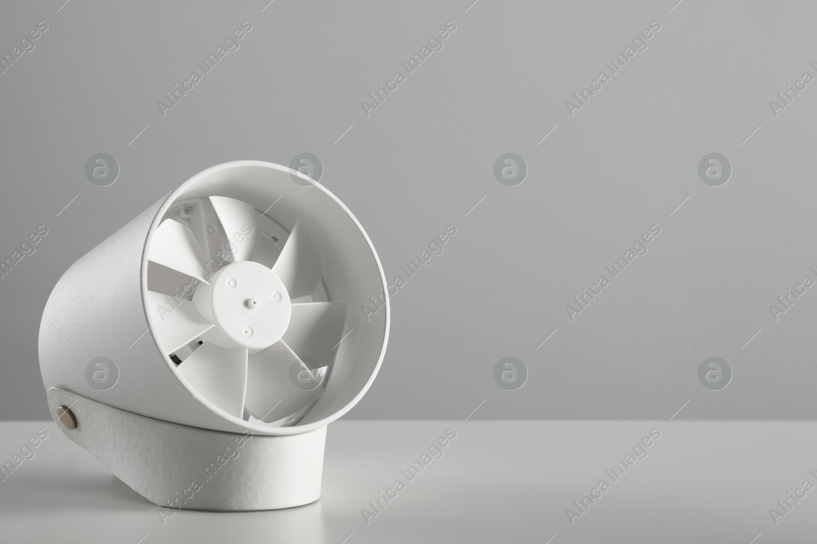 Photo of Portable fan on table against light grey background, space for text. Summer heat