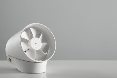 Portable fan on table against light grey background, space for text. Summer heat