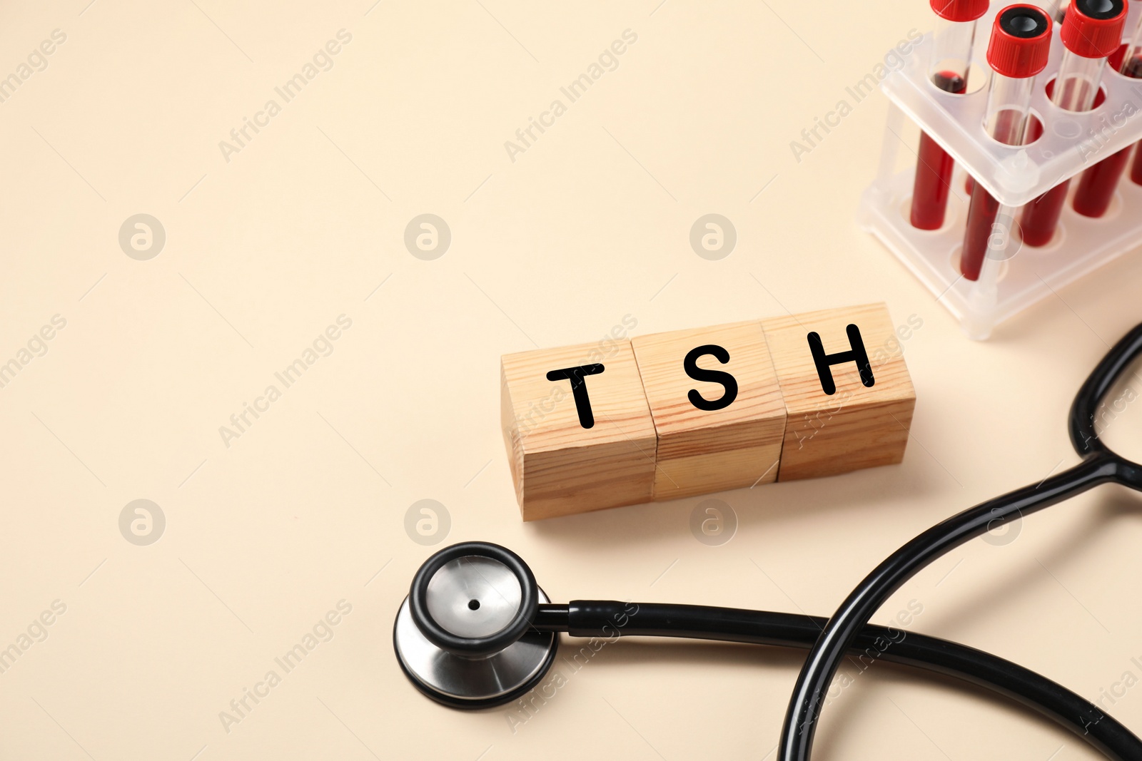 Photo of Endocrinology. Stethoscope, wooden cubes with thyroid hormones and blood samples in test tubes on beige background. Space for text