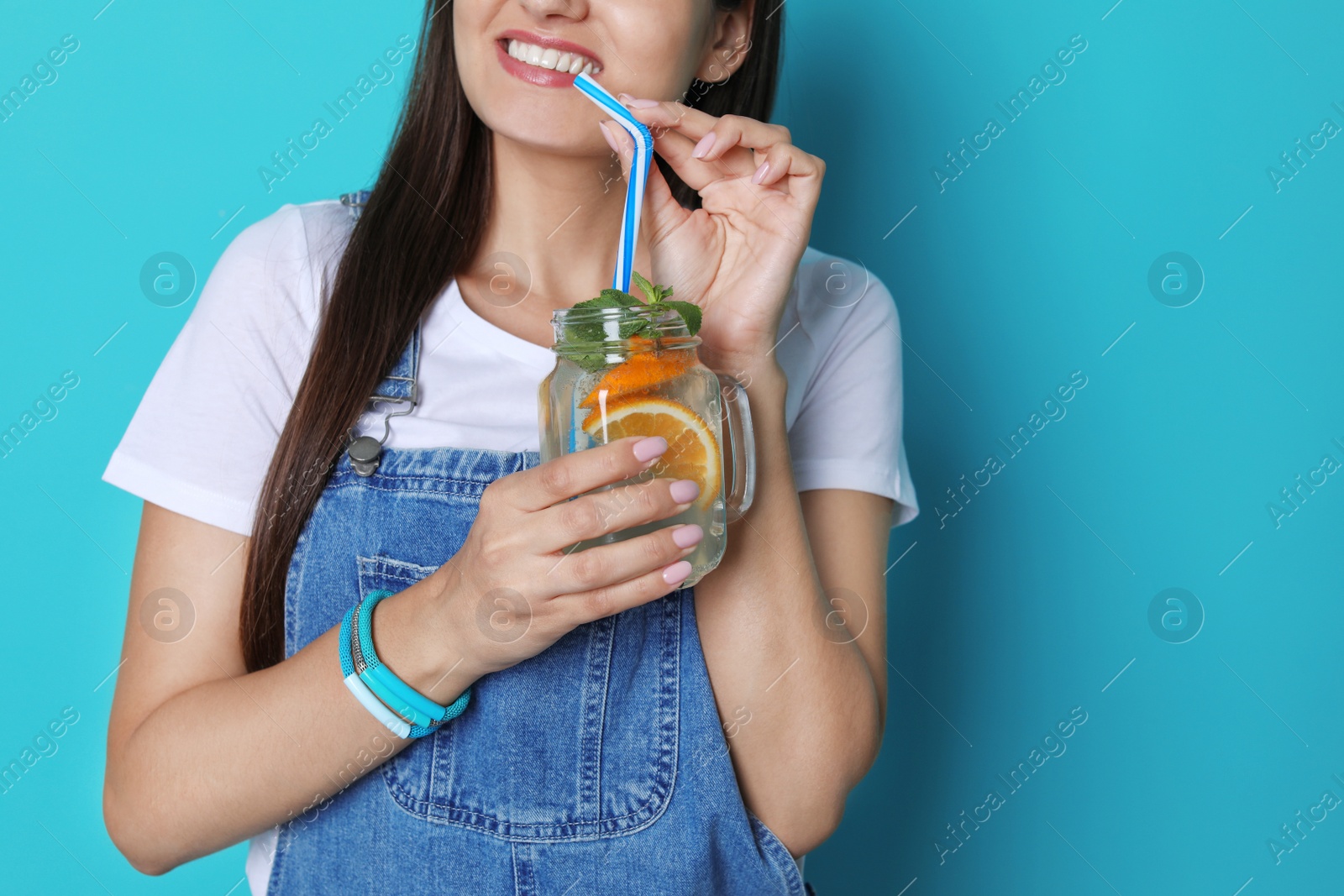 Photo of Young woman with mason jar of tasty lemonade on color background. Natural detox drink