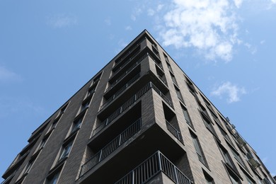 Modern building with big windows against blue sky outdoors, low angle view