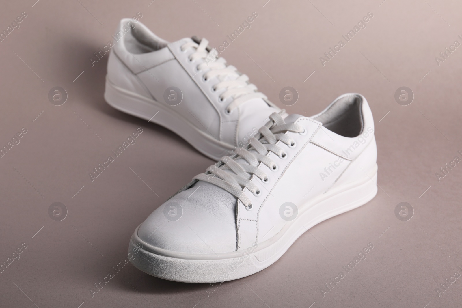 Photo of Pair of stylish white sneakers on grey background