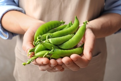 Photo of Young woman holding fresh green peas, closeup