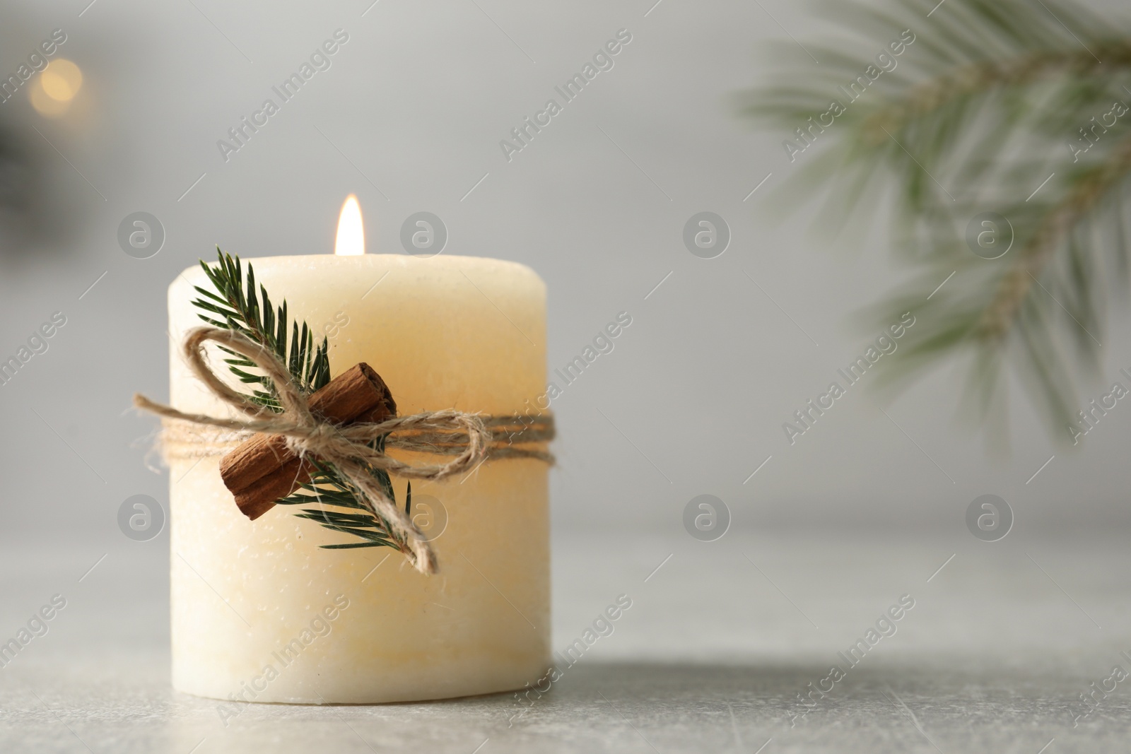 Photo of Burning candle with pinecone scent on light grey table, closeup. Space for text