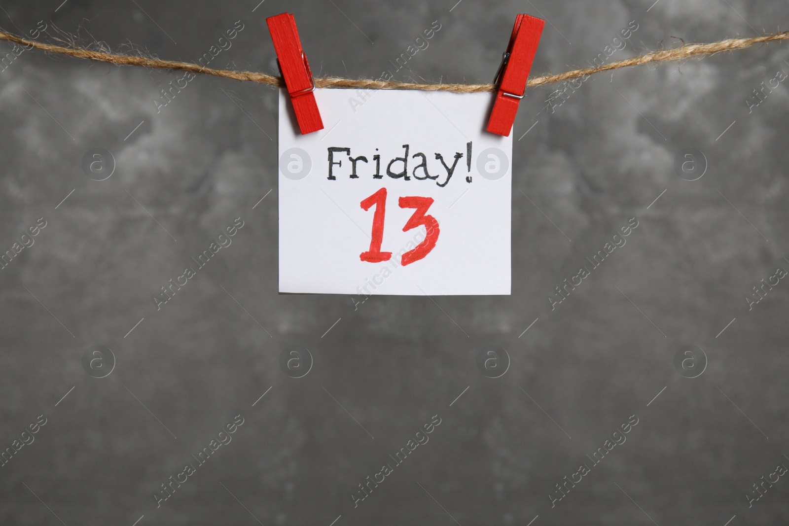 Photo of Paper note with phrase Friday! 13 hanging on twine against grey background, space for text. Bad luck superstition