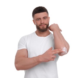 Photo of Handsome man applying body cream onto his elbow on white background