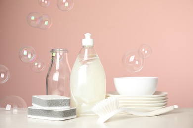 Photo of Cleaning tools, plates and soap bubbles on pink background. Dish washing supplies
