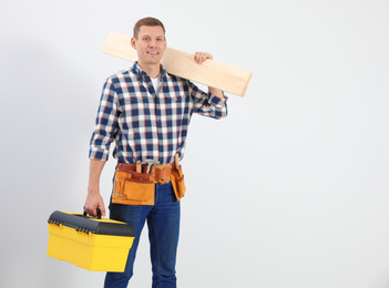 Handsome carpenter with wooden planks on light background. Space for text