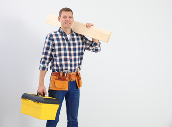 Photo of Handsome carpenter with wooden planks on light background. Space for text