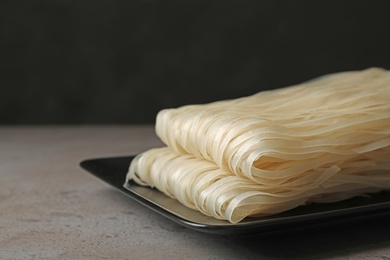 Photo of Plate with raw rice noodles on table, closeup. Space for text