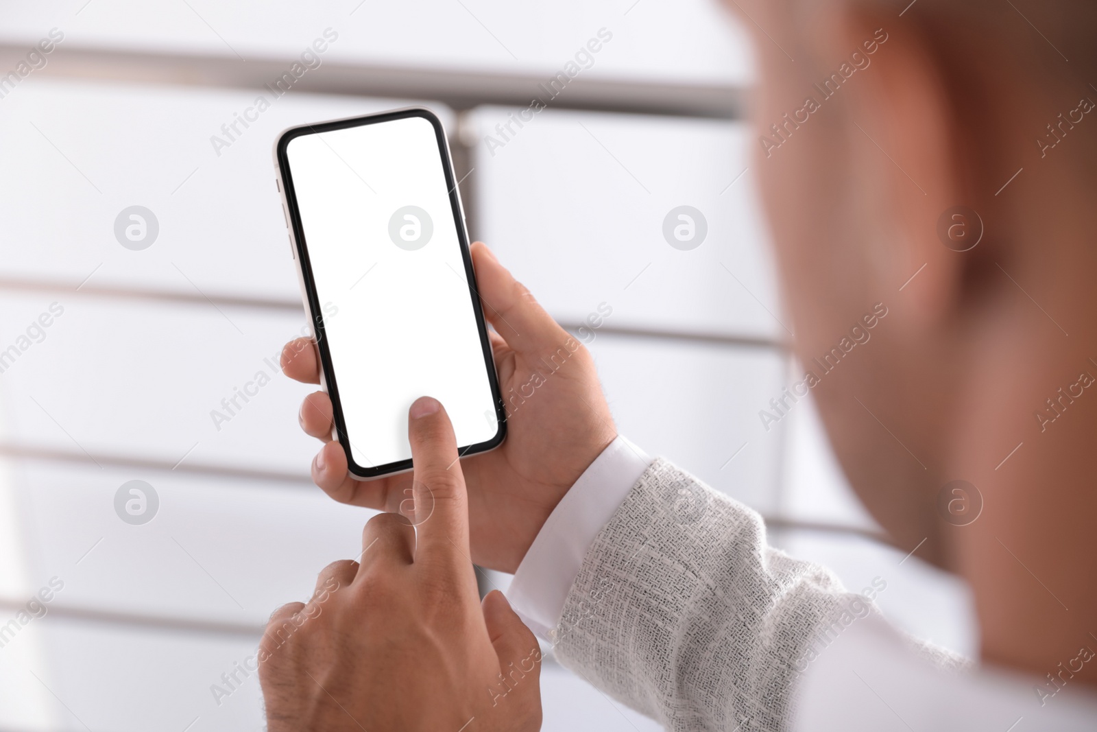 Photo of Man using mobile phone with empty screen indoors, closeup