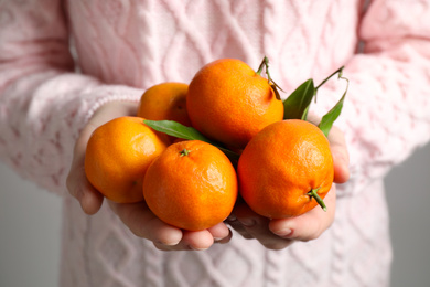 Photo of Woman holding pile of tangerines, closeup. Juicy citrus fruit