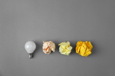 Flat lay composition with lamp bulb and crumpled paper on grey background