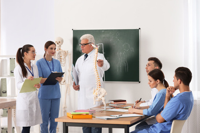 Medical students and professor studying human spine structure in classroom