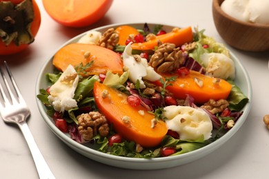 Photo of Delicious persimmon salad with cheese and pomegranate served on white table