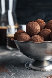 Photo of Bowl with tasty chocolate truffles on grey table