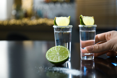 Woman with shot glasses of Mexican Tequila on black table at bar, closeup