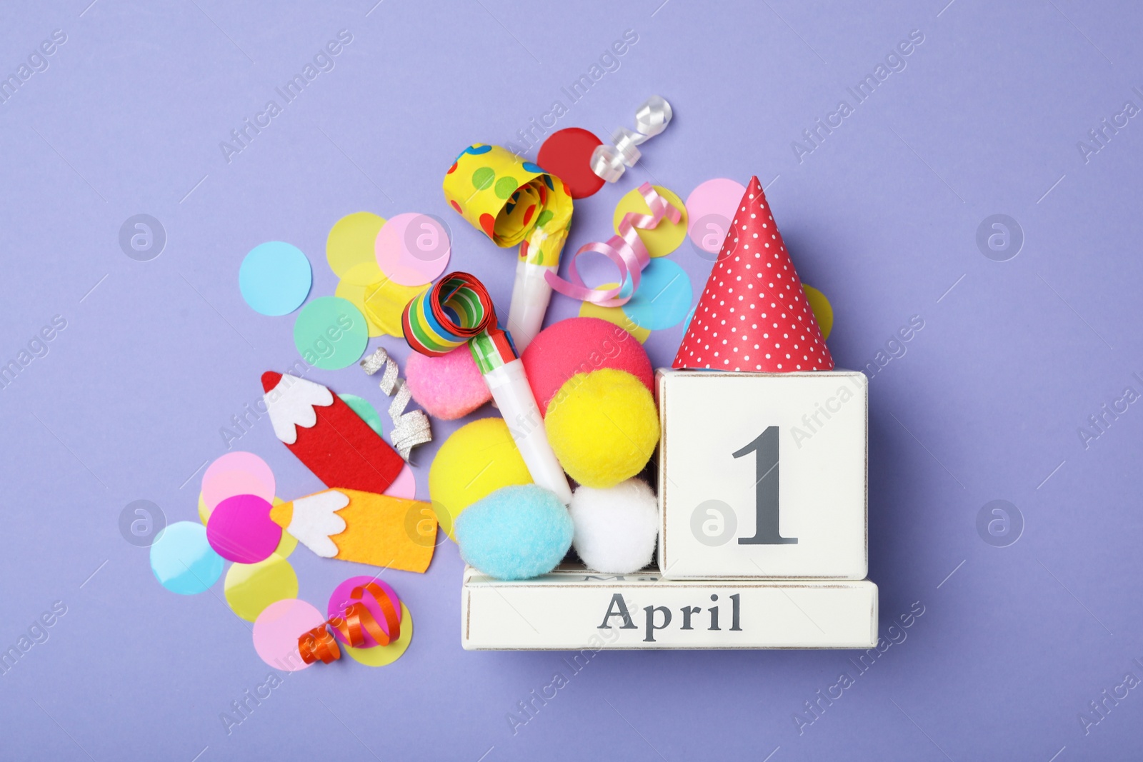 Photo of Flat lay composition with block calendar and party items on violet background. April Fool's Day