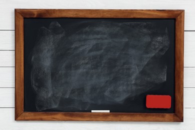 Photo of Dirty black chalkboard hanging on white wooden wall
