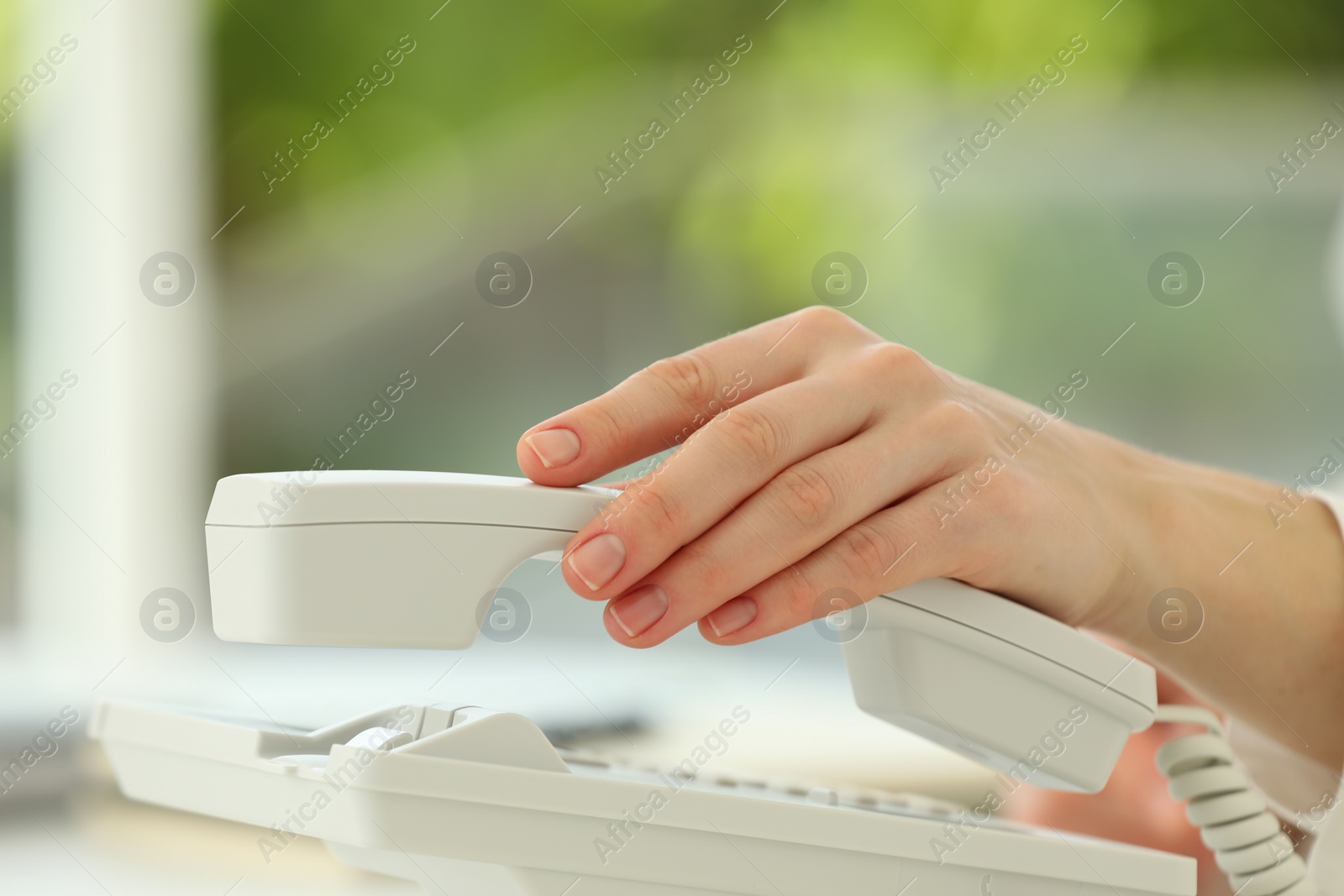 Photo of Assistant taking telephone handset on blurred background, closeup