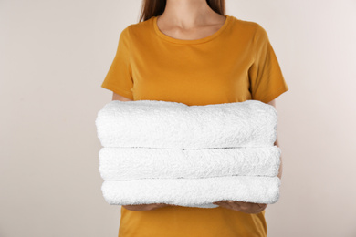 Woman holding fresh towels on light background, closeup