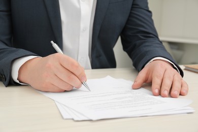 Photo of Man signing document at wooden table, closeup