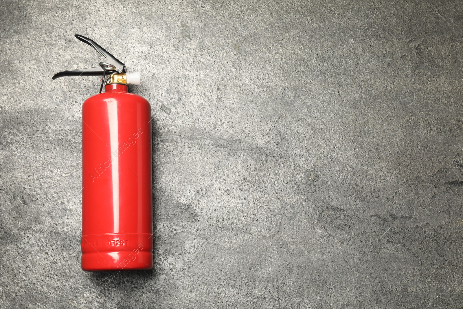 Photo of One red fire extinguisher on gray textured background, top view. Space for text