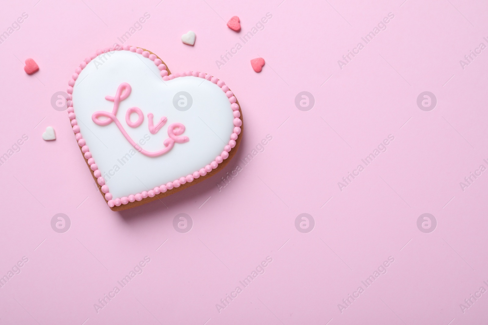 Photo of Heart shaped cookie with word Love on pink background, flat lay and space for text. Valentine's day treat