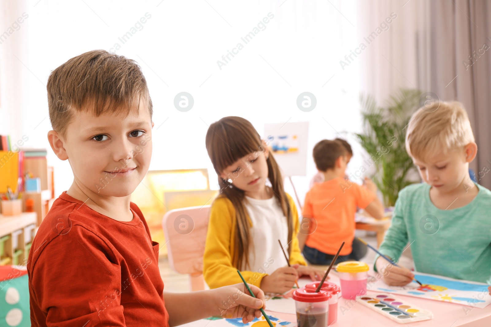 Photo of Cute little children painting at table in room