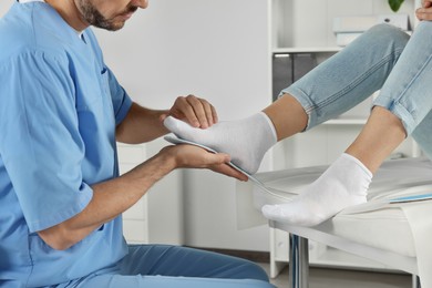 Photo of Male orthopedist fitting insole to patient's foot in hospital, closeup