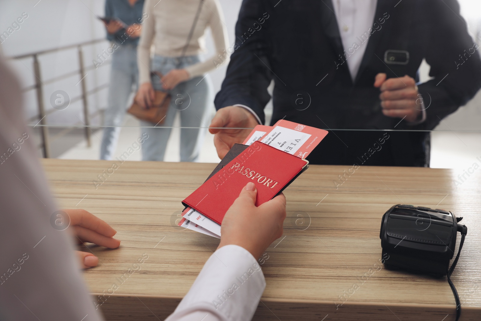 Photo of Agent giving passports with tickets to client at check-in desk in airport, closeup